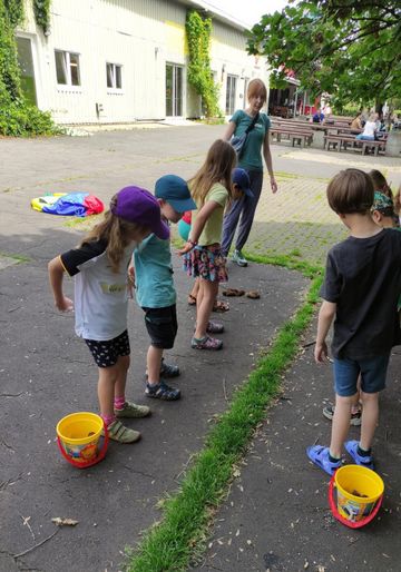 Kinder spielen draußen ein Spiel über die Nahrungsaufnahme von Raupen