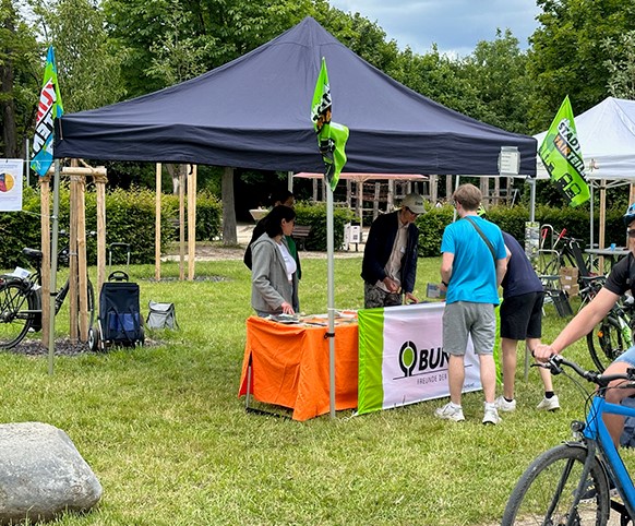 Auf dem Foto ist der Stand des Kreisverbands BUND Frankfurt an der Nidda beim GrünGürtel-Fahrradtag 2024 abgebildet. Fahrradfahrer holen sich ihre Stempel ab und schauen sich Infomaterial an.
